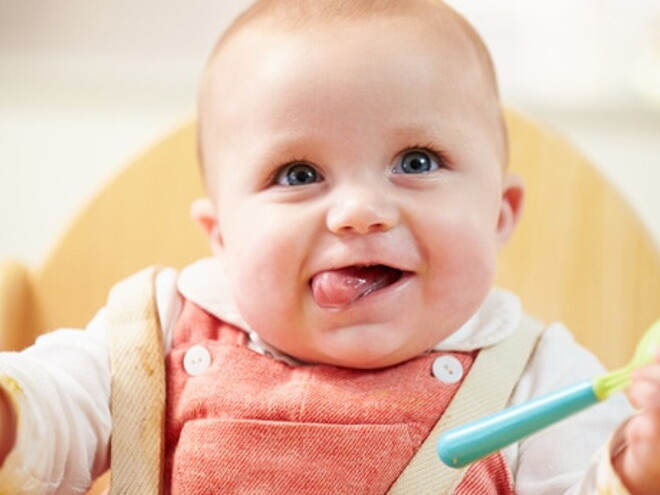 bebe dans chaise haute avec sa cuillère